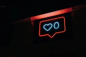 Uma placa de neon em formato de notificação do Instagram. Dentro há um coração, com o número zero ao lado.
